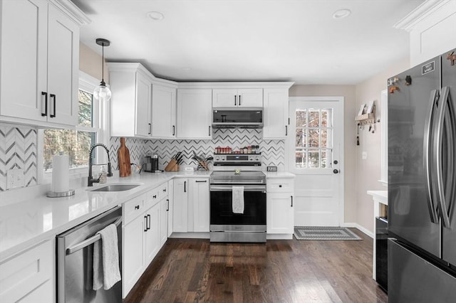 kitchen with dark wood finished floors, decorative light fixtures, stainless steel appliances, white cabinetry, and a sink