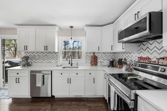 kitchen featuring hanging light fixtures, appliances with stainless steel finishes, light countertops, and white cabinets