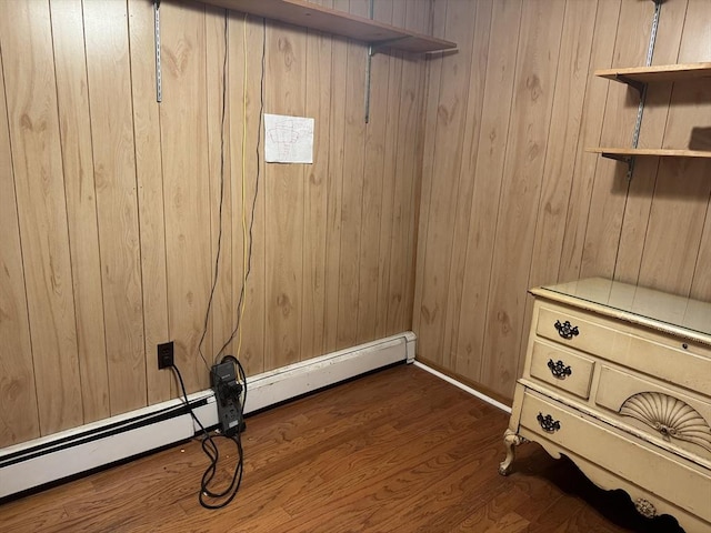 interior space with wood walls, dark wood-style floors, and a baseboard heating unit
