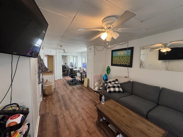 living area featuring wood finished floors, a drop ceiling, and ceiling fan