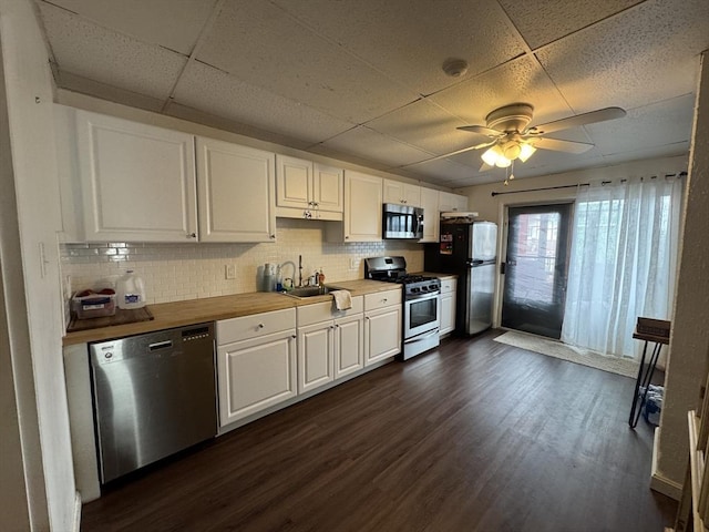 kitchen with a paneled ceiling, white cabinetry, appliances with stainless steel finishes, and tasteful backsplash