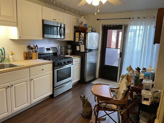 kitchen with appliances with stainless steel finishes, tasteful backsplash, sink, white cabinets, and dark hardwood / wood-style floors