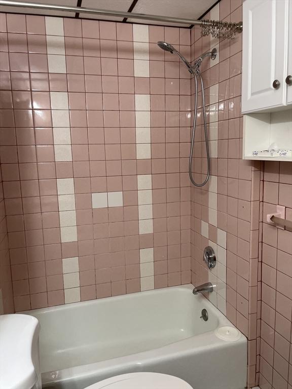 bathroom with toilet and tiled shower / bath