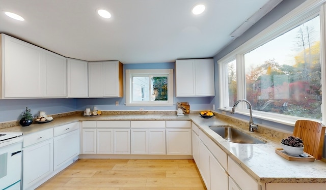 kitchen featuring light hardwood / wood-style flooring, white cabinetry, sink, and plenty of natural light