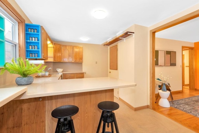 kitchen with sink, light hardwood / wood-style flooring, a kitchen bar, and kitchen peninsula