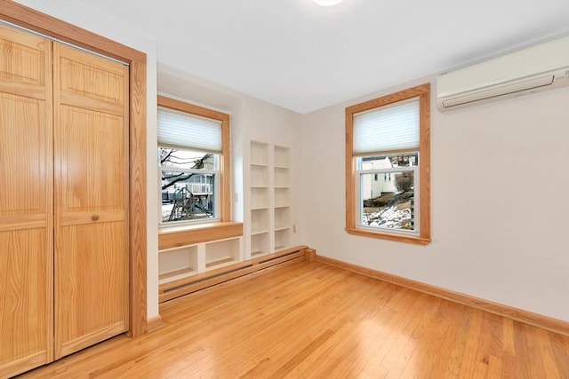 unfurnished bedroom featuring a baseboard radiator, light hardwood / wood-style floors, and a wall mounted AC