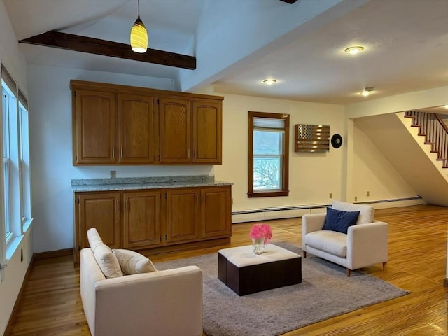 living area with light wood finished floors, stairway, a baseboard heating unit, vaulted ceiling, and baseboards