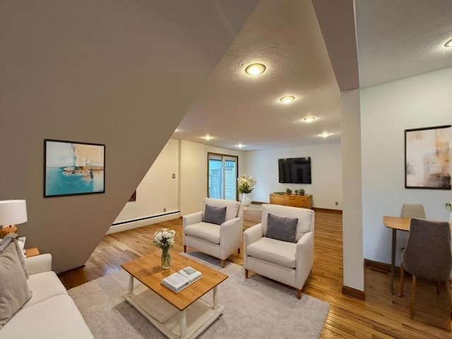 living area featuring a textured ceiling, light wood finished floors, a baseboard radiator, and baseboards