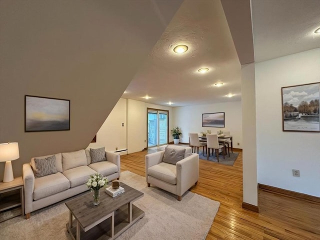 living area featuring a textured ceiling, light wood-type flooring, and baseboards