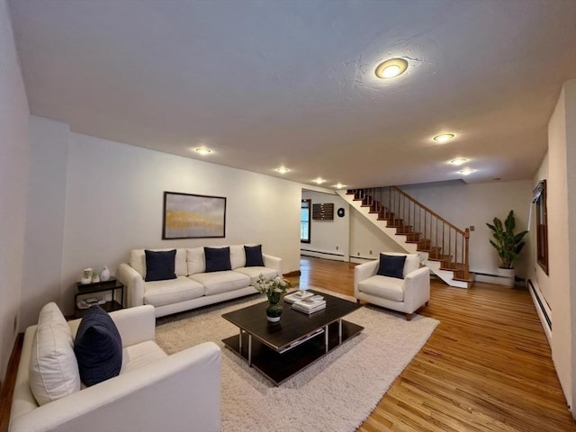 living area with stairs, a baseboard heating unit, wood finished floors, and recessed lighting