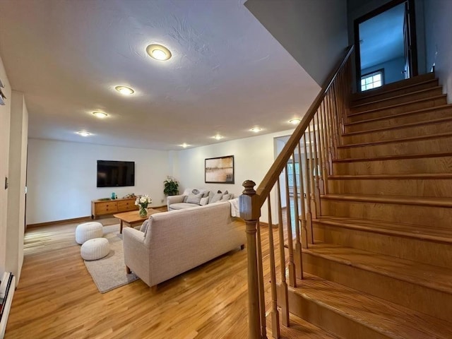 living area with light wood-style floors, stairs, baseboards, and baseboard heating