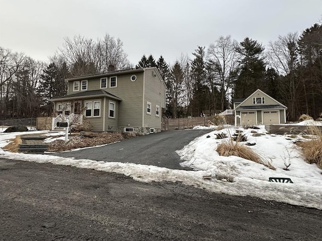 view of front of home featuring an outbuilding, a chimney, a detached garage, and fence