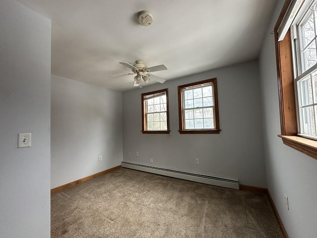 carpeted empty room with a baseboard radiator, a ceiling fan, and baseboards