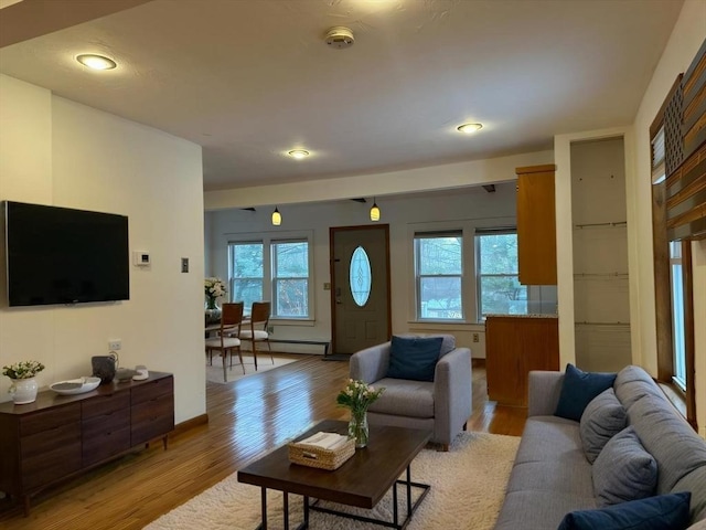 living area with light wood-type flooring, baseboards, and baseboard heating