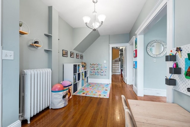 rec room with radiator heating unit, hardwood / wood-style floors, and a notable chandelier