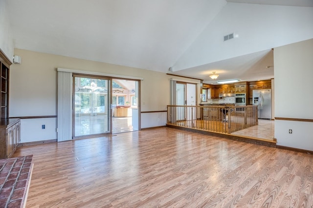 unfurnished living room with high vaulted ceiling and light hardwood / wood-style floors