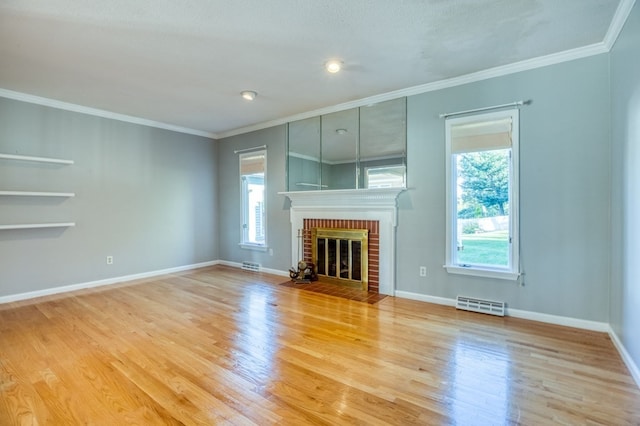 unfurnished living room with a healthy amount of sunlight, light hardwood / wood-style floors, ornamental molding, and a brick fireplace