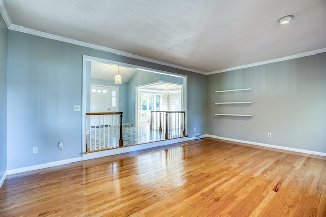 unfurnished living room with hardwood / wood-style floors, ornamental molding, and a notable chandelier