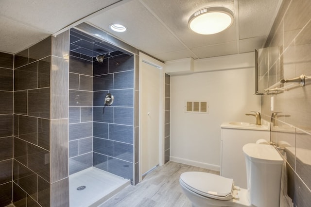 bathroom with toilet, hardwood / wood-style floors, vanity, and tiled shower