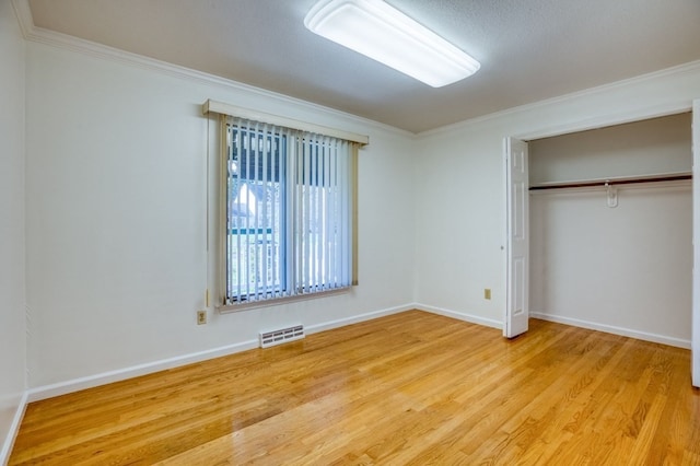 unfurnished bedroom with light hardwood / wood-style floors, a closet, and crown molding