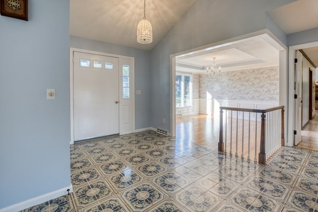 entrance foyer with tile patterned floors, vaulted ceiling, a raised ceiling, and an inviting chandelier