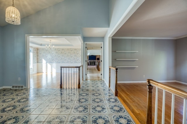 hall featuring crown molding, hardwood / wood-style floors, and a notable chandelier