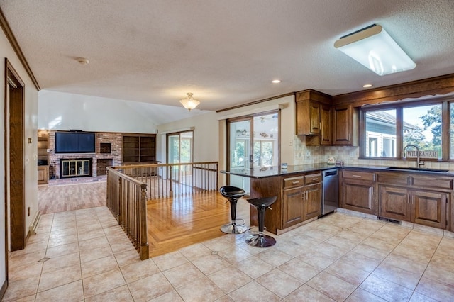 kitchen featuring plenty of natural light, dishwasher, kitchen peninsula, and a textured ceiling