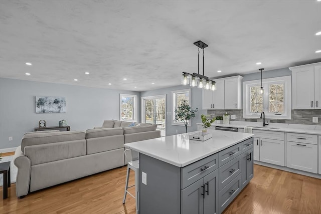 kitchen featuring light hardwood / wood-style flooring, sink, a center island, white cabinetry, and hanging light fixtures