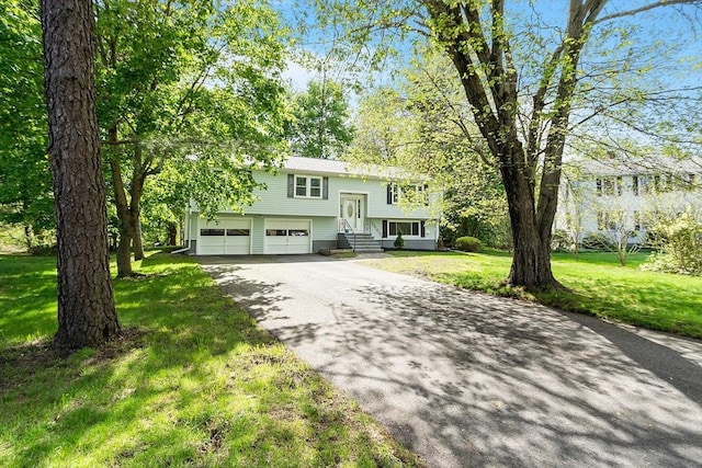 split foyer home with asphalt driveway, an attached garage, entry steps, and a front lawn