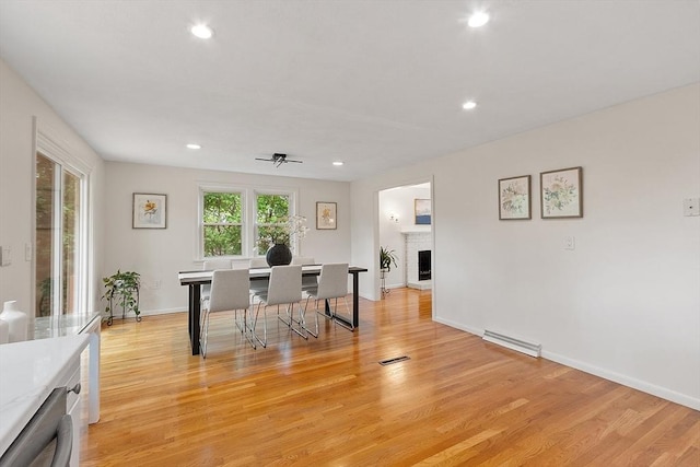 dining room with recessed lighting, light wood-style floors, a brick fireplace, and baseboards
