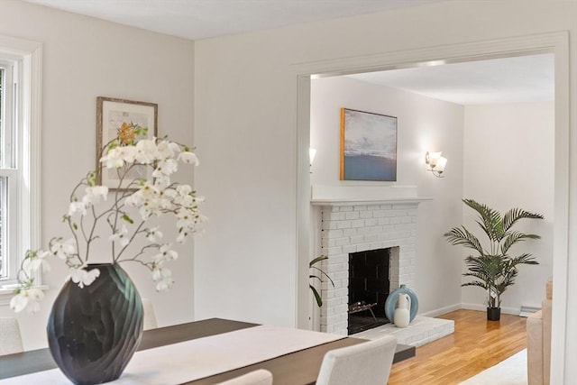 dining room featuring wood finished floors, a brick fireplace, and baseboards