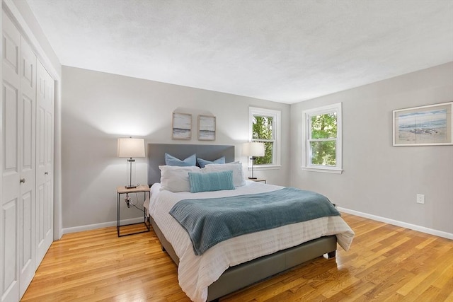 bedroom featuring baseboards, light wood finished floors, and a closet