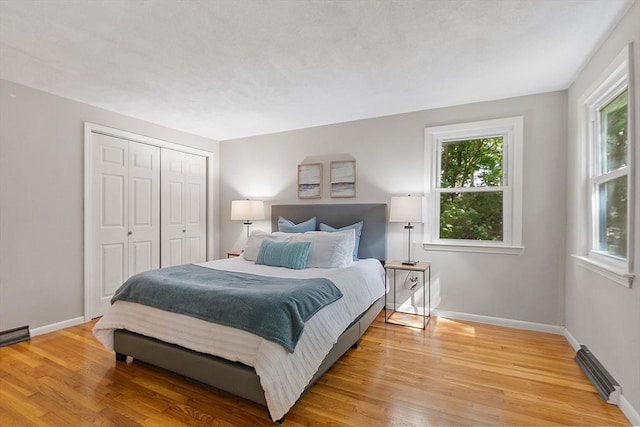 bedroom with light wood-style floors, a closet, and baseboards