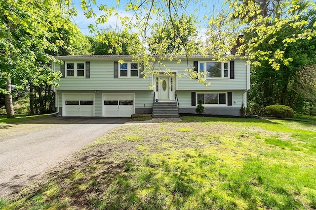raised ranch with entry steps, asphalt driveway, a front yard, and an attached garage