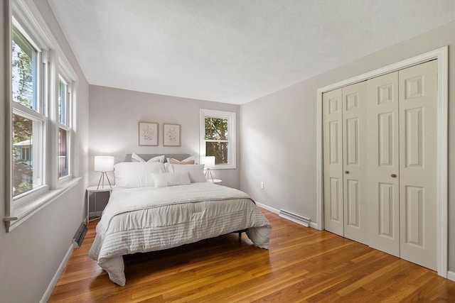 bedroom with multiple windows, baseboards, and wood finished floors