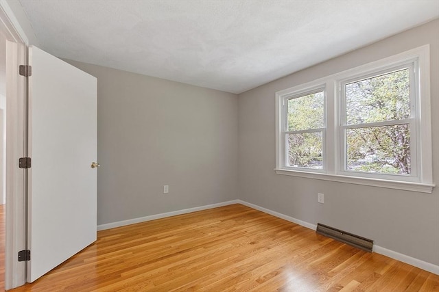 empty room featuring light wood-type flooring and baseboards