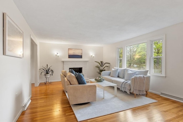 living area with light wood-type flooring, a fireplace, baseboards, and a baseboard heating unit