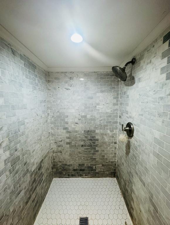 bathroom featuring crown molding and a tile shower