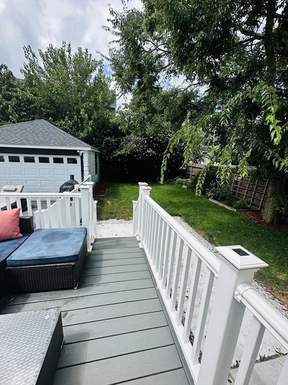 wooden deck with a garage, a yard, and an outbuilding