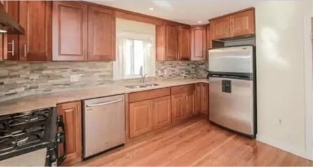 kitchen featuring dishwashing machine, light hardwood / wood-style flooring, sink, gas stove, and stainless steel refrigerator