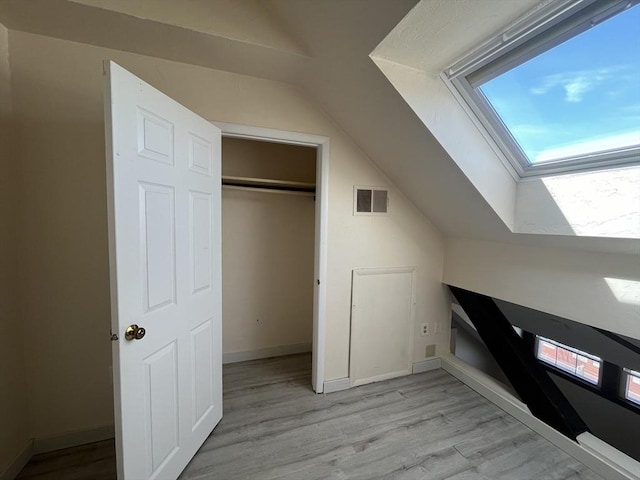 bonus room with baseboards, visible vents, lofted ceiling with skylight, and light wood finished floors