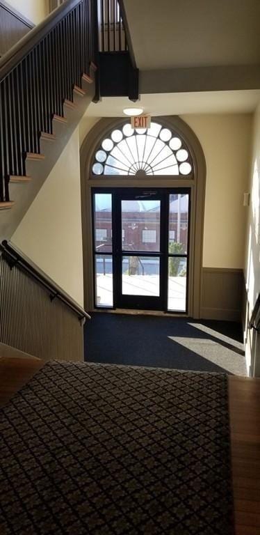 foyer entrance with stairs and a wainscoted wall