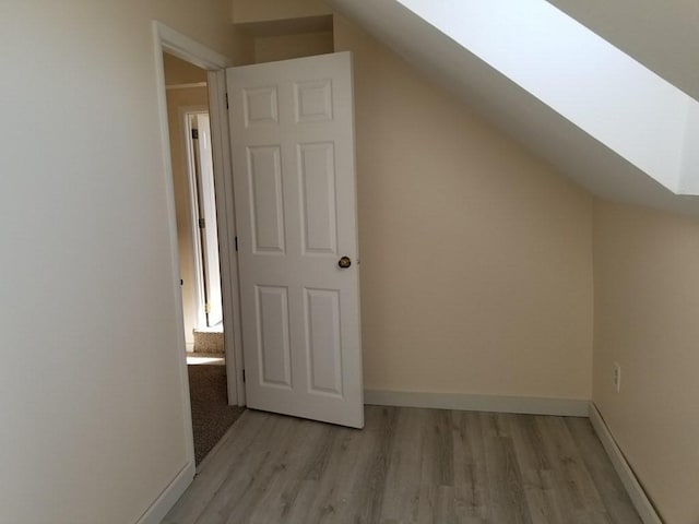 bonus room with baseboards, light wood-style flooring, and a skylight