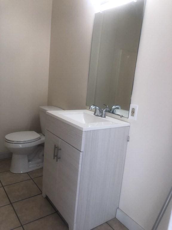 bathroom with toilet, vanity, and tile patterned floors