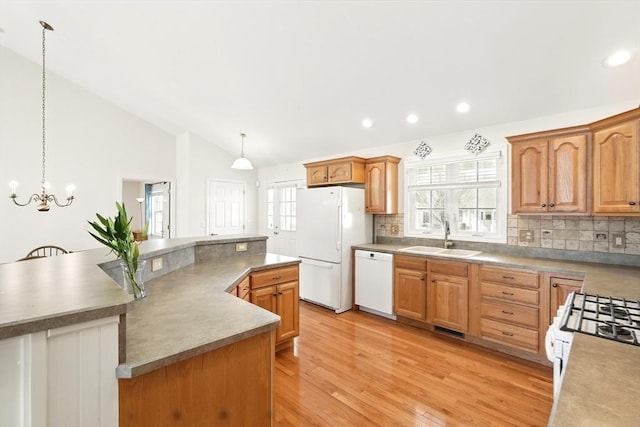 kitchen featuring a healthy amount of sunlight, white appliances, lofted ceiling, and a sink