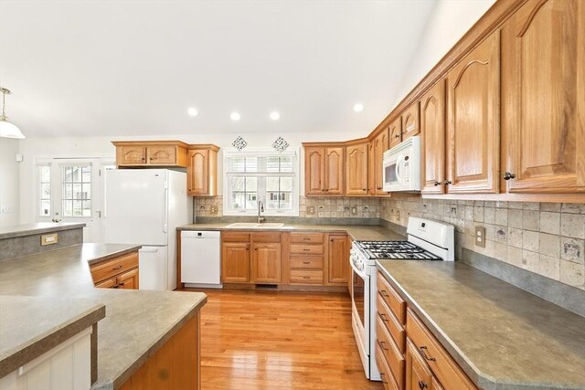 kitchen featuring a sink, white appliances, light wood-style floors, and plenty of natural light