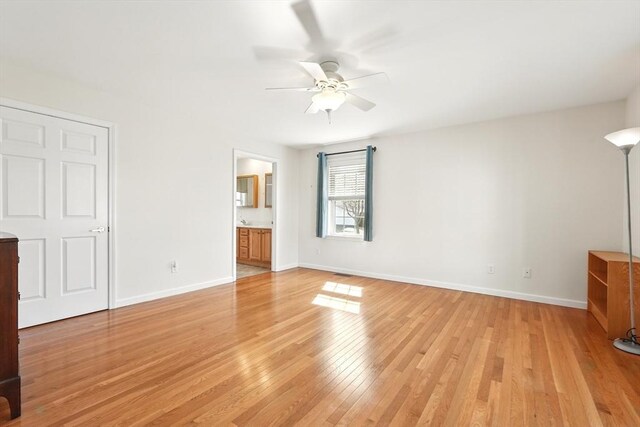 unfurnished bedroom with ensuite bath, baseboards, light wood-style floors, and a ceiling fan