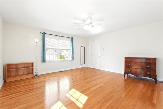 unfurnished room with baseboards, light wood-style flooring, and a ceiling fan