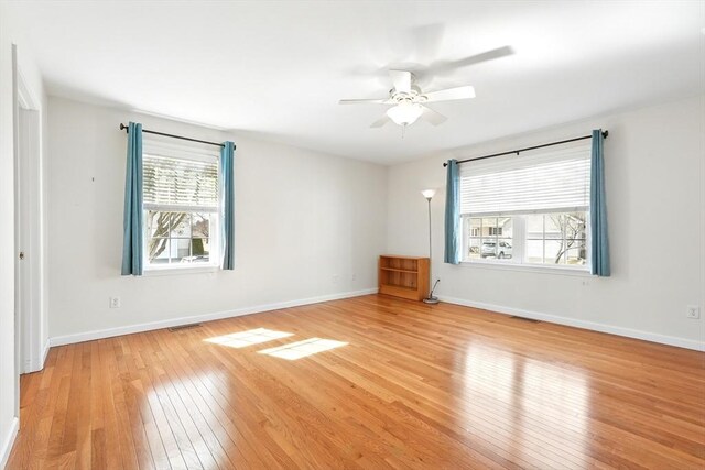 empty room with visible vents, light wood-type flooring, and baseboards