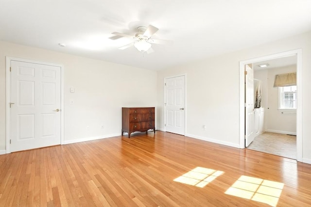 empty room with a ceiling fan, light wood-style floors, and baseboards